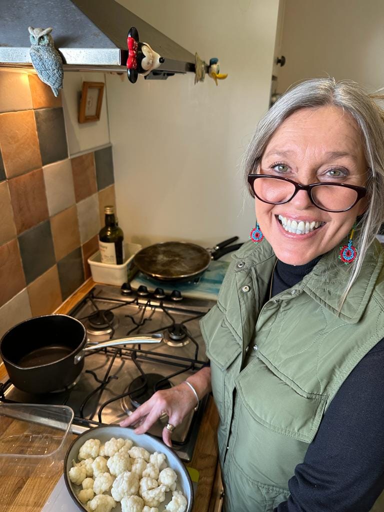 A cheerful support partner preparing a meal in a client's kitchen