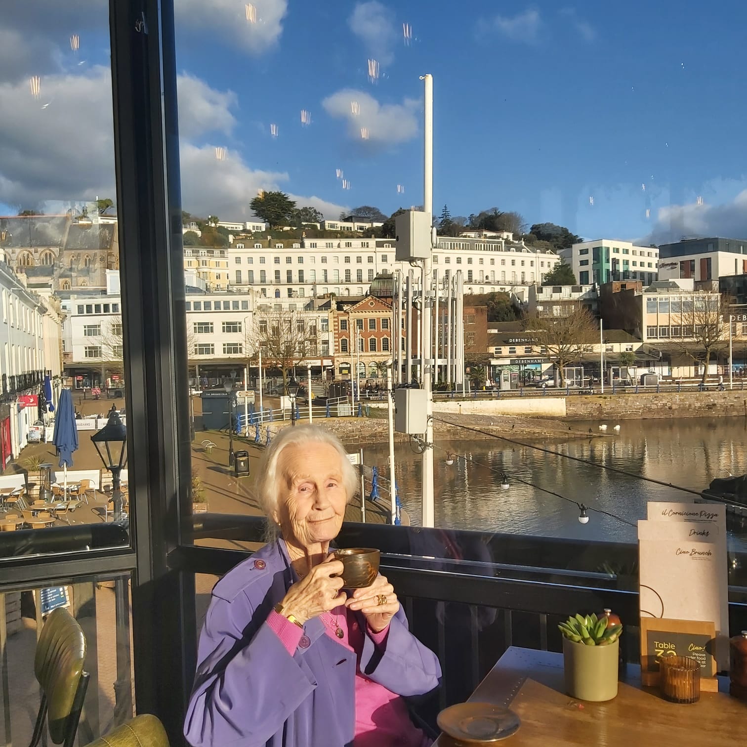 A client enjoying a cup of tea overlooking the harbour with her carer